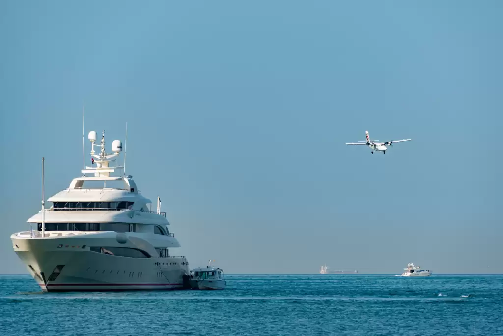 A superyacht anchored off Monaco with tender boat and aircraft overhead, highlighting the scale, access, and travel experience of a Monaco yacht charter.
