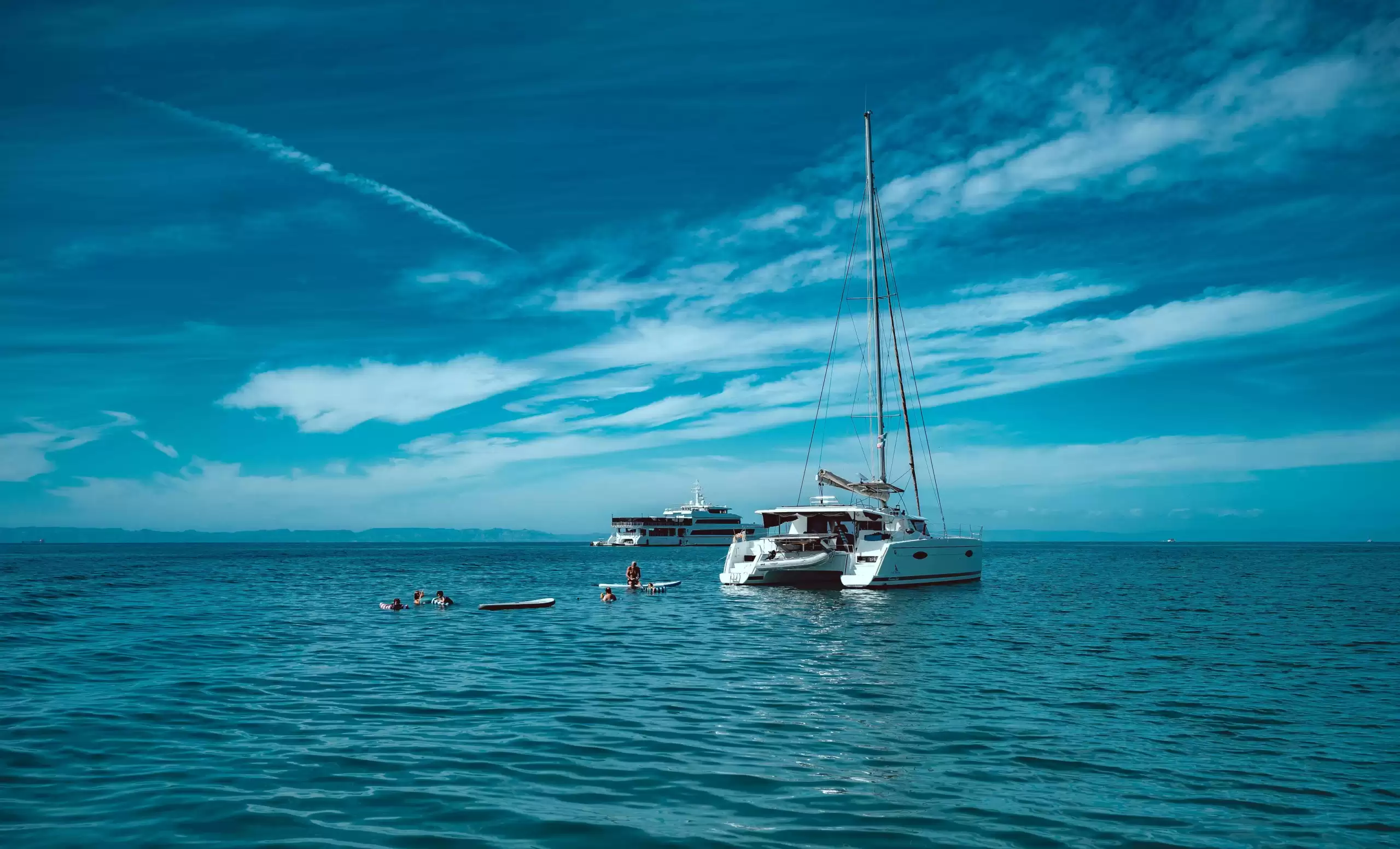 Catamaran rental in Monaco anchored on clear Mediterranean waters while guests swim and relax during a private French Riviera charter.